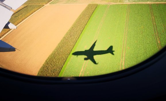 Aeriel view of an airplane shadow looking out of an airplane window over a field